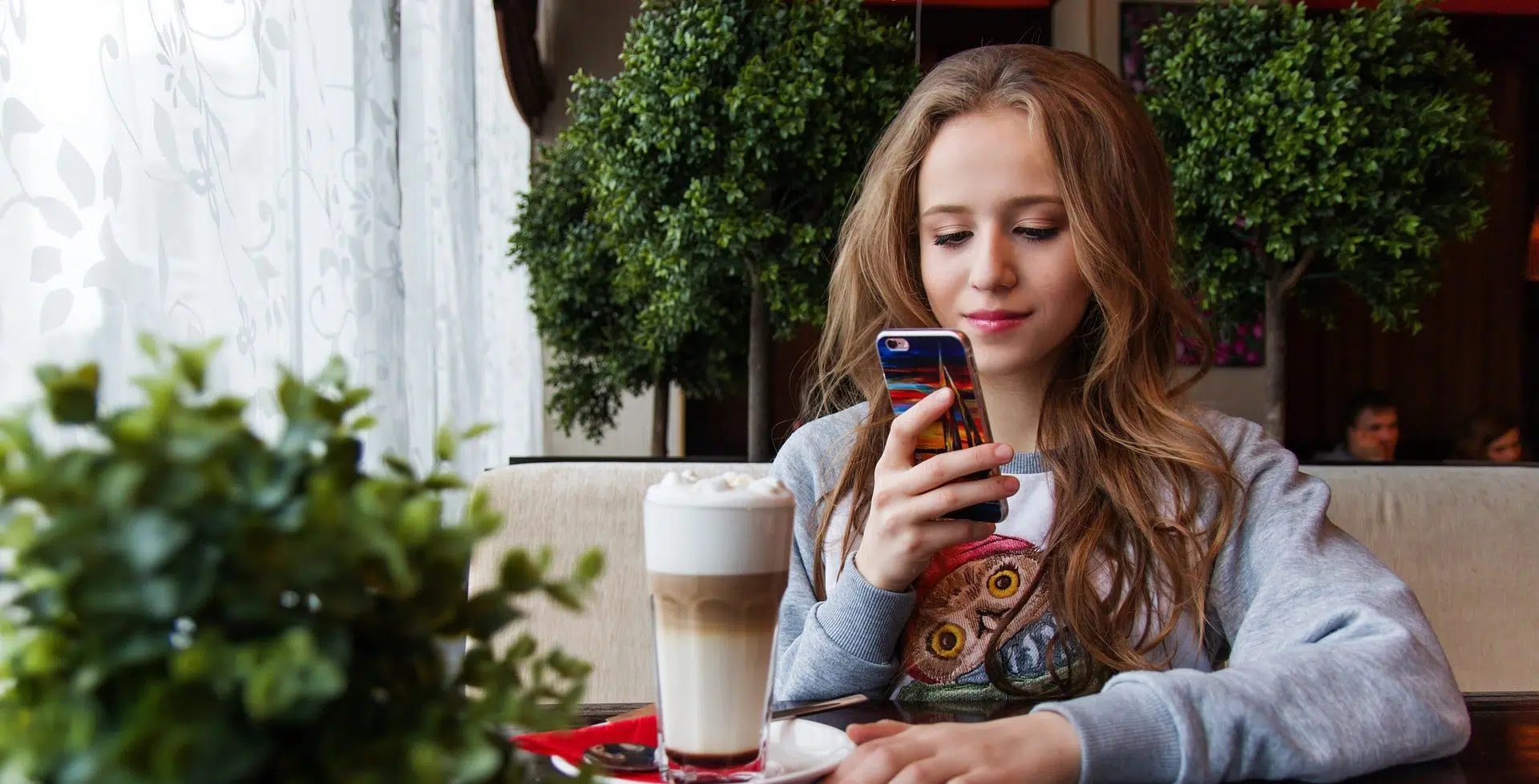 teenage girl on her phone in a coffee shop