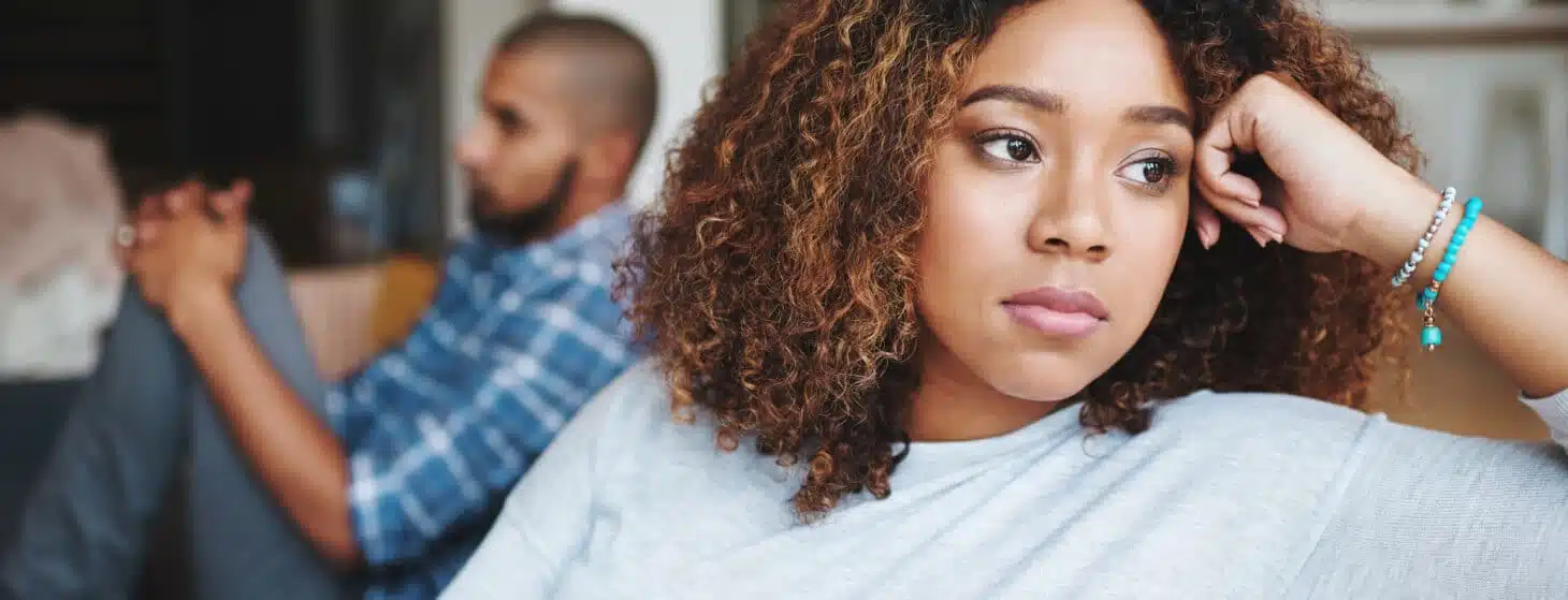 Unhappy couple and sad woman upset after argument or conflict with her man on home sofa. Angry girlfriend or female thinking about disagreement or ignoring partner, tired of relationship problems